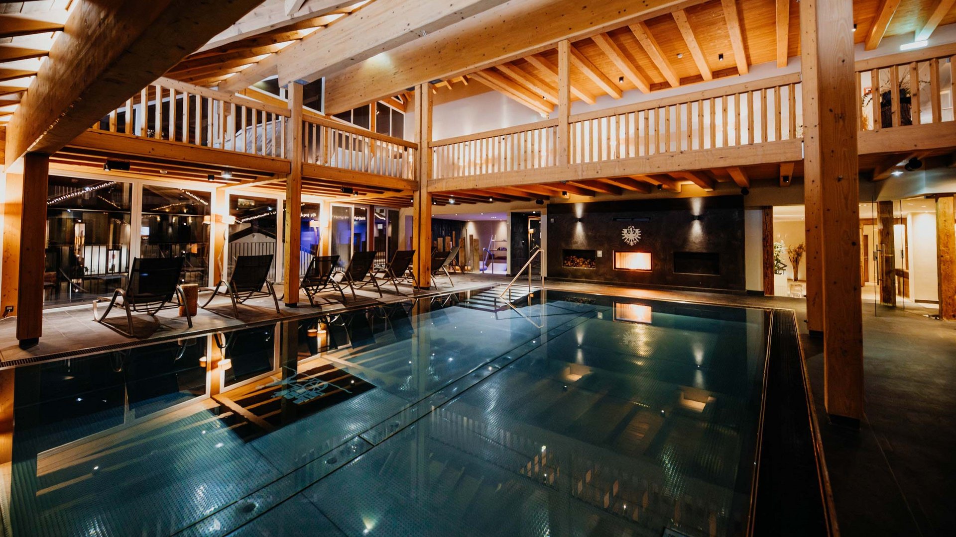 Piscina interna con soffitto in legno e camino in centro benessere moderno